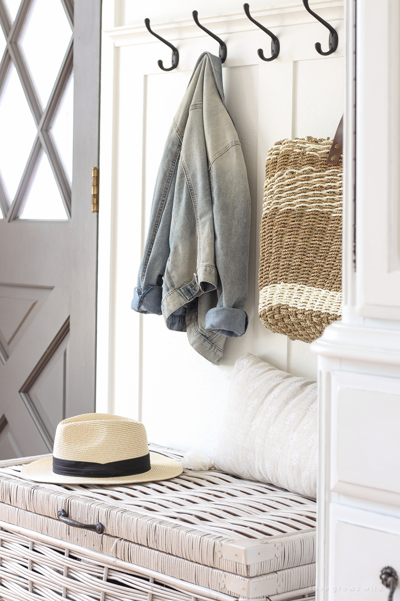 Beautiful styled entryway with coat hooks and wicker trunk