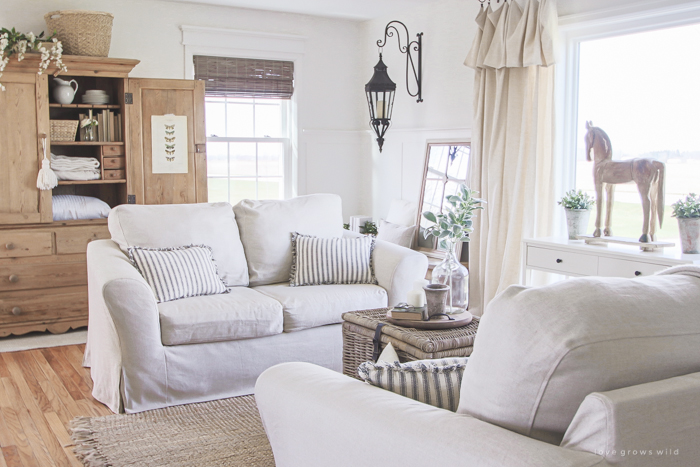 A cozy farmhouse living room with beautiful linen slipcovered sofas. See how to get this custom slipcovered look at LoveGrowsWild.com!