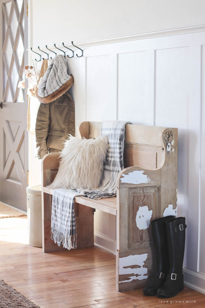 This simple farmhouse entryway is perfectly decorated for winter with large coat hooks, a rustic bench, and a place for snow-covered boots. See more photos at LoveGrowsWild.com