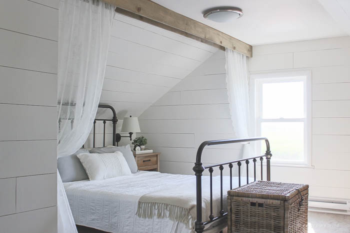 This cozy sleeping nook was created by adding a faux wood beam and lace curtains over the bed, and the results are amazing! See how to do this project in your home at LoveGrowsWild.com